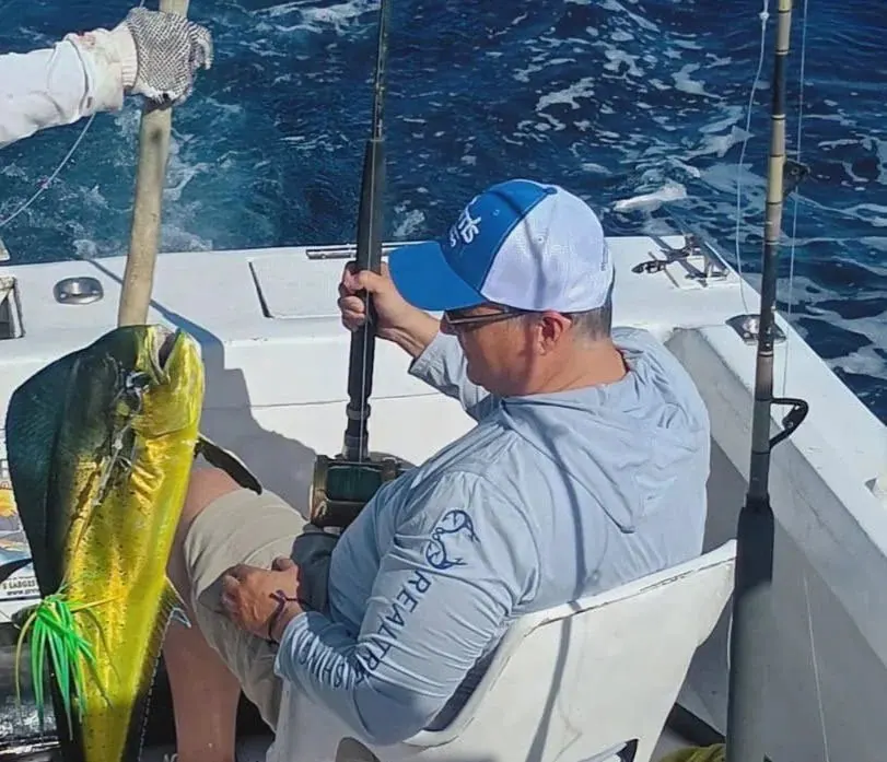 Angler fighting a fish from the chair next to a dorado, May 2025