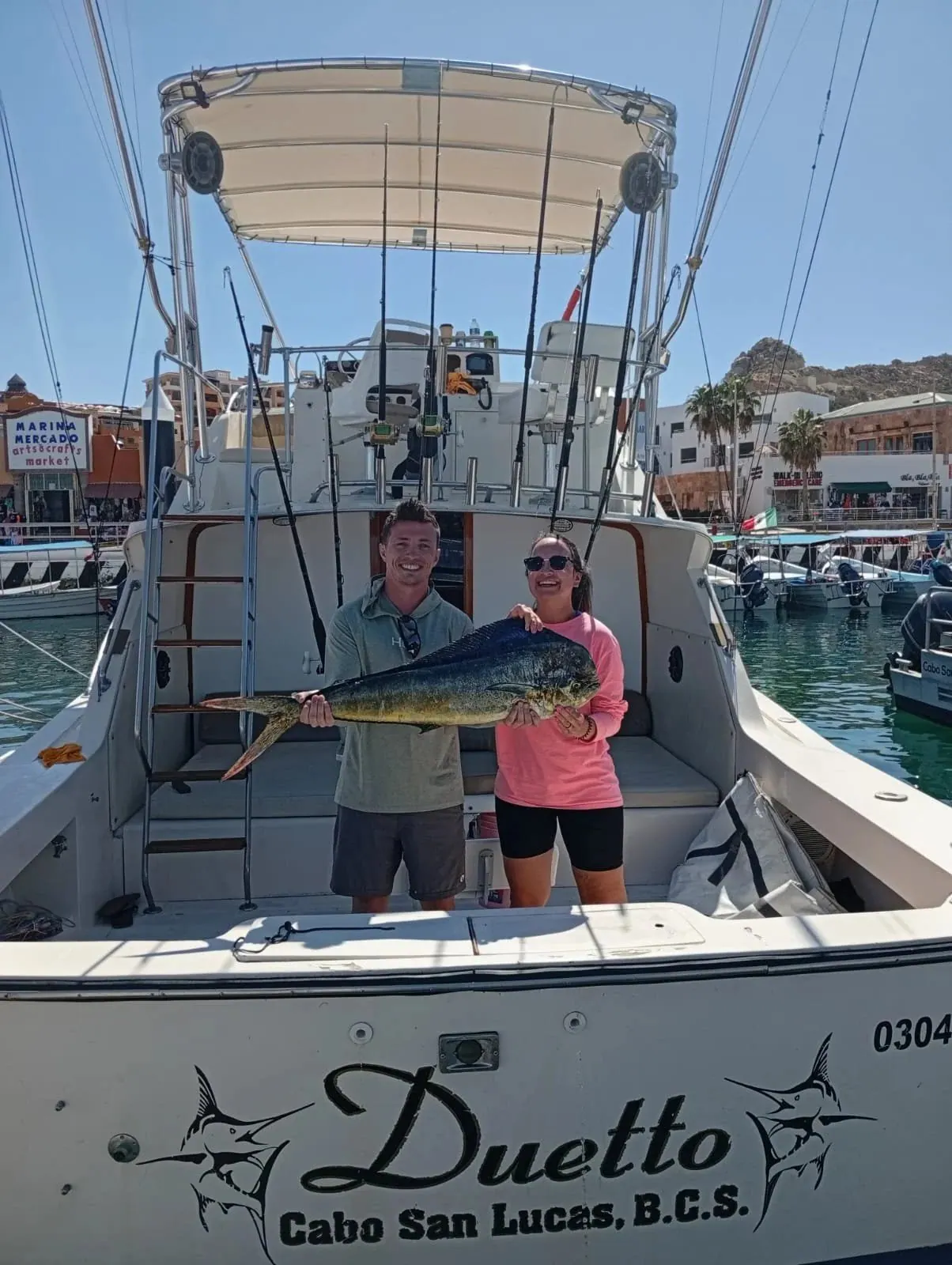 Couple with a dorado aboard the Duetto at the marina, early March 2026