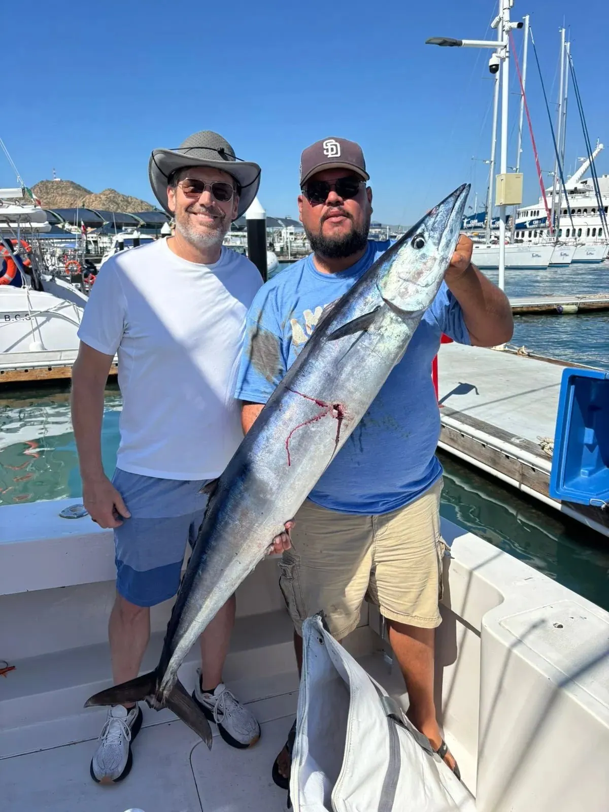 Two anglers with a wahoo at the marina, November 2025