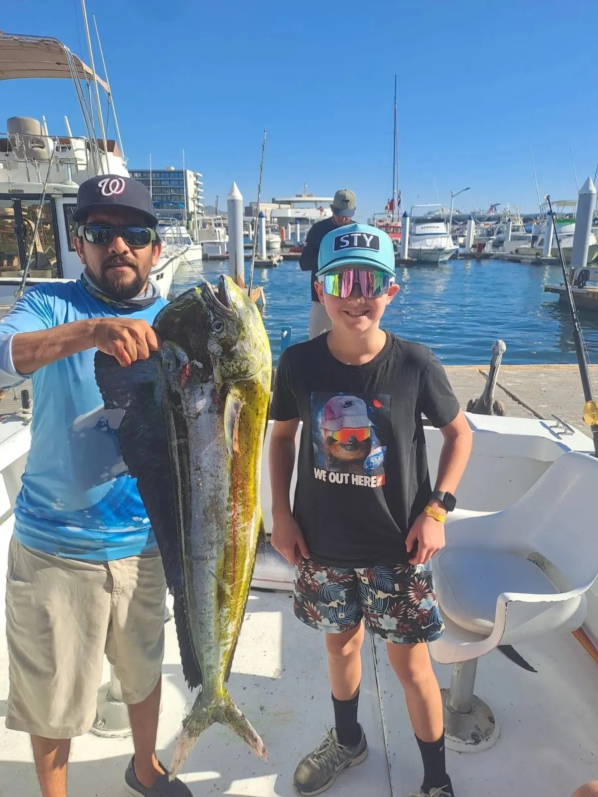 Father and son with a dorado at the marina, December 2025