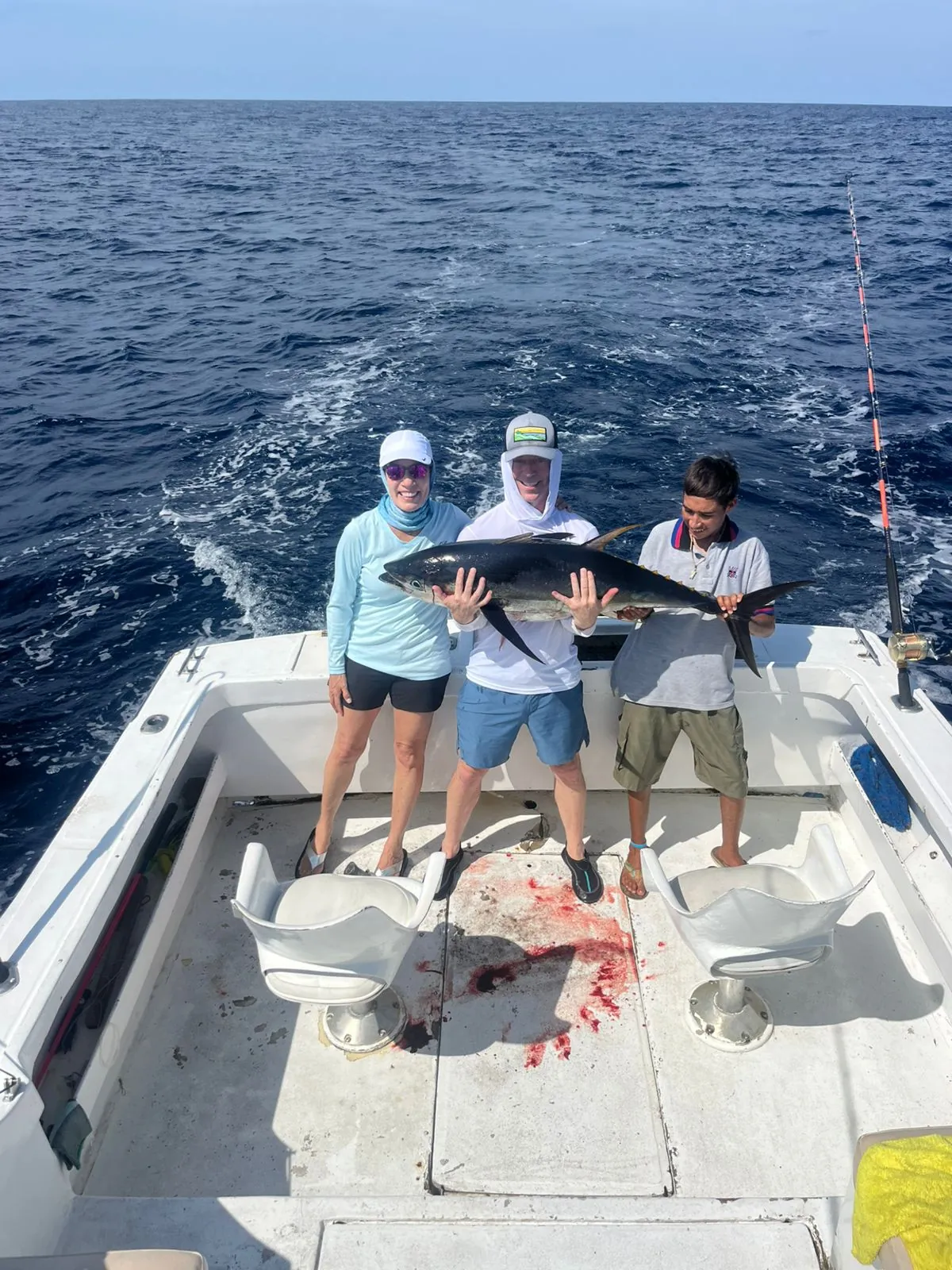 Three anglers holding a big yellowfin tuna, late August 2026