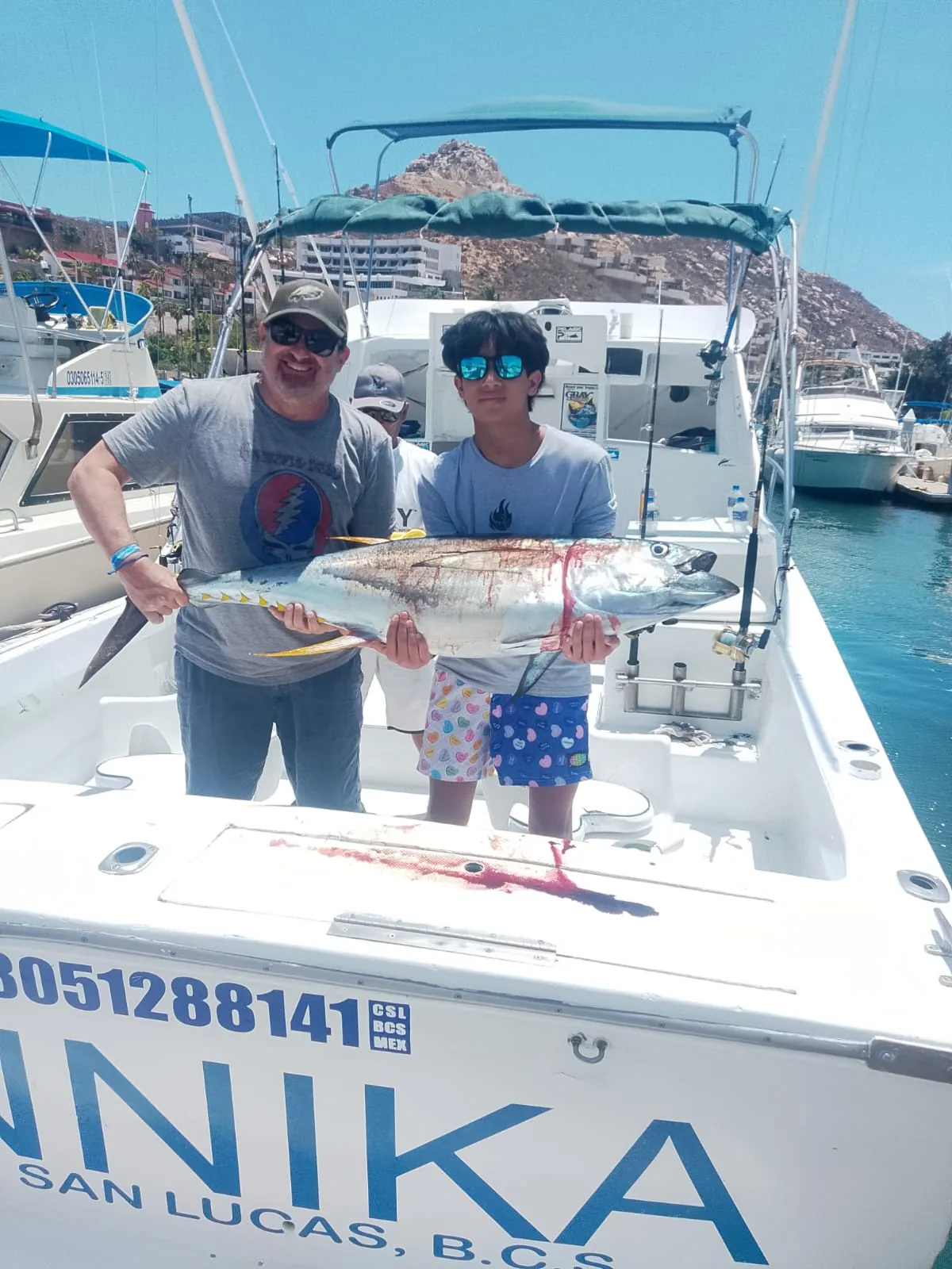 Father and son with a yellowfin tuna at the dock, August 2026