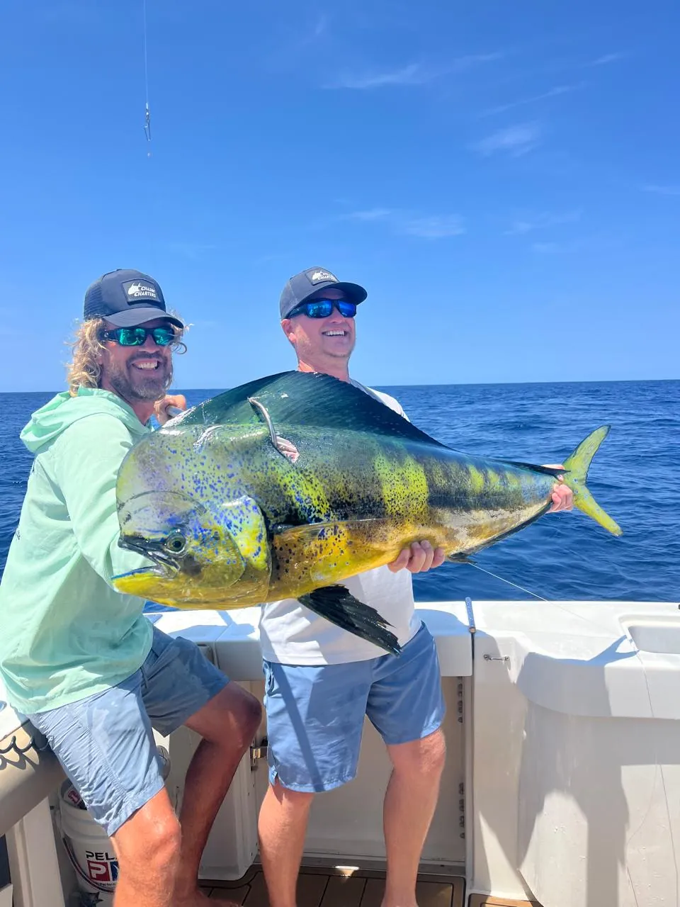 Two anglers with a bull dorado, late August 2026