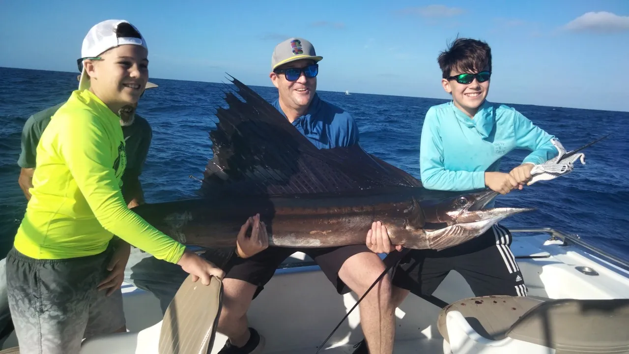 Three young anglers with a sailfish, October 2026