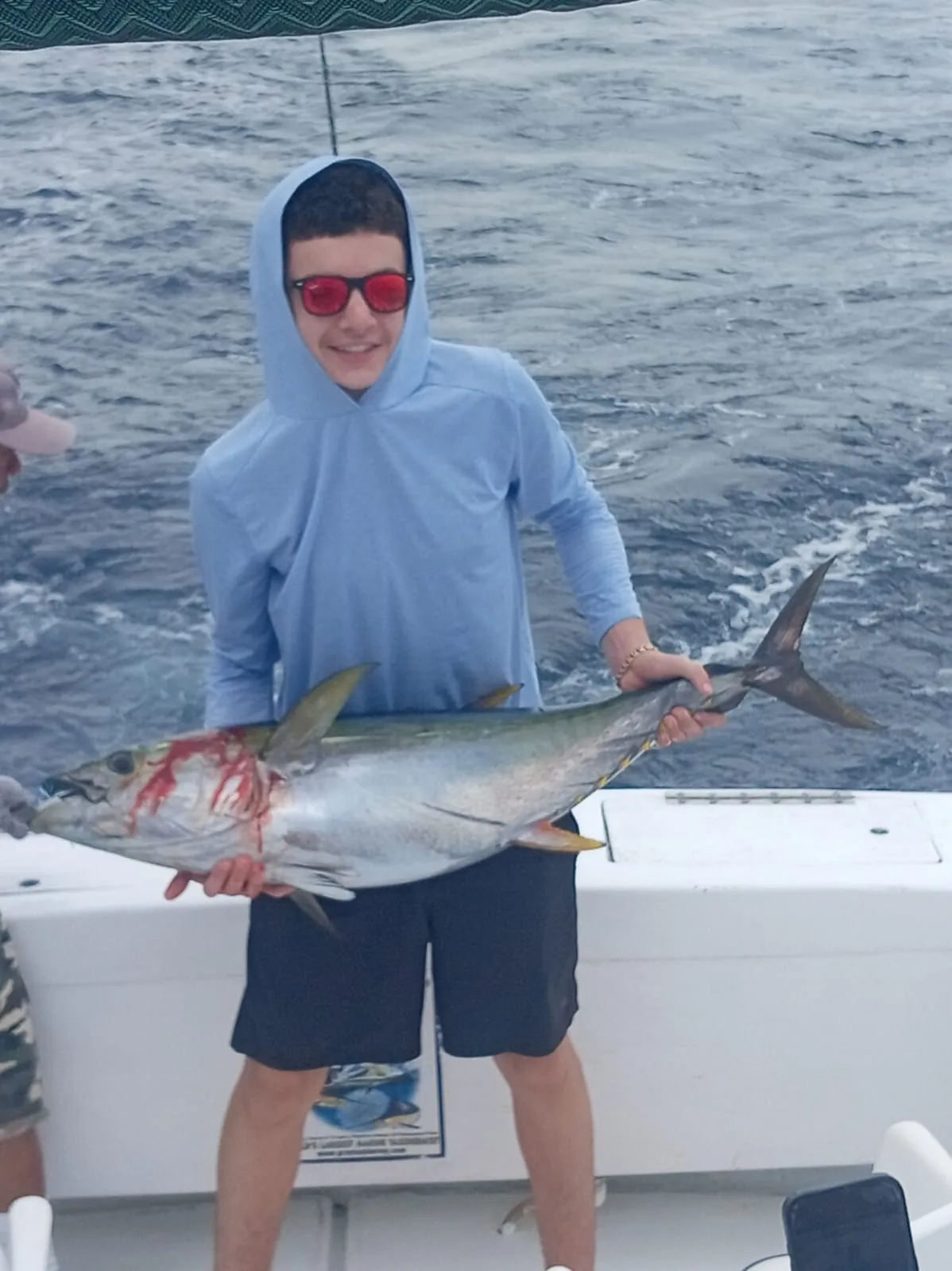 Teenage angler with a yellowfin tuna, late July 2026