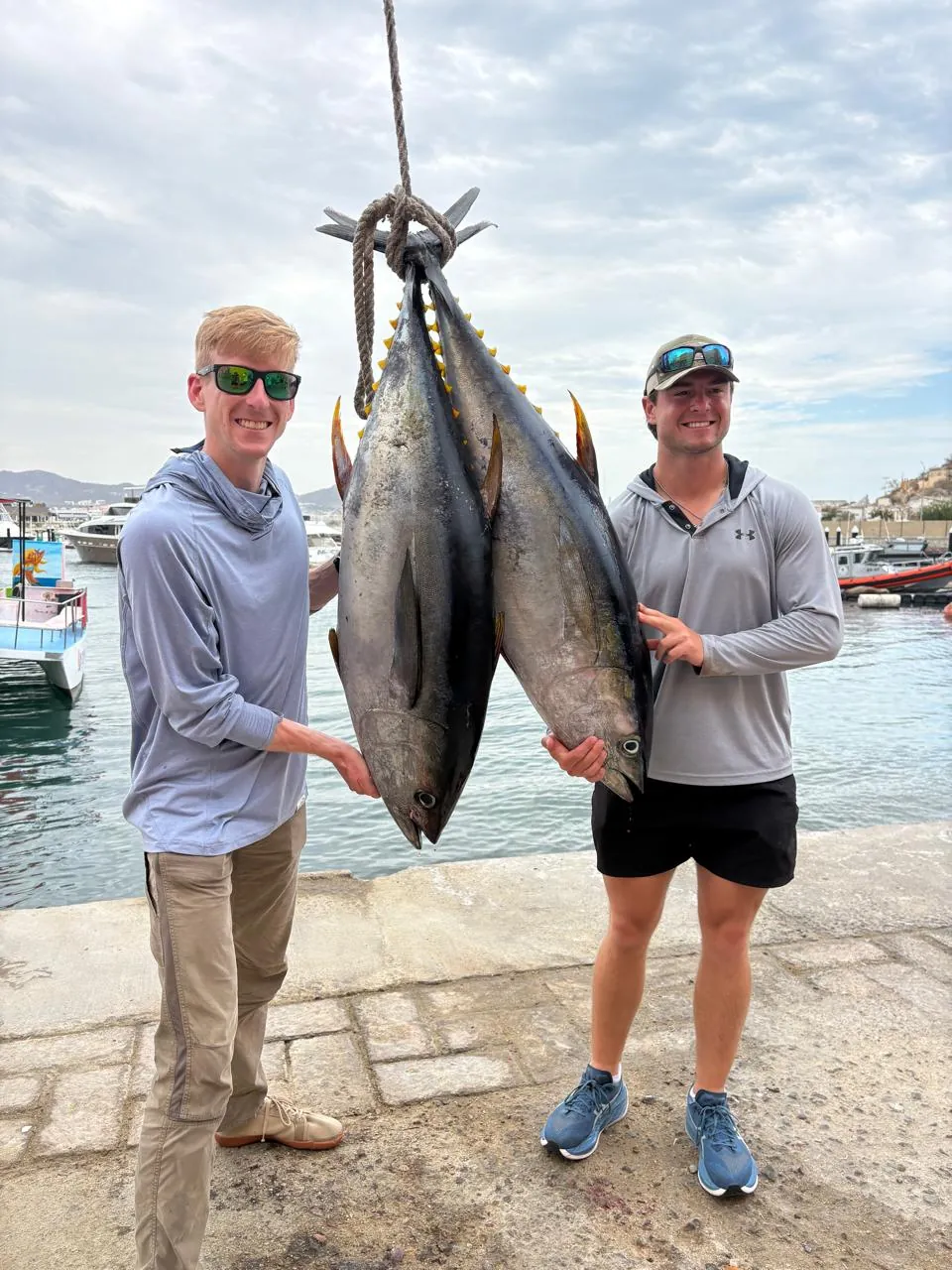Two anglers with a pair of yellowfin tuna at the dock, late July 2026