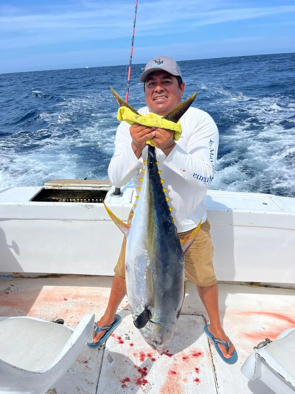 Crew member with a yellowfin tuna and the catch flag, July 2026